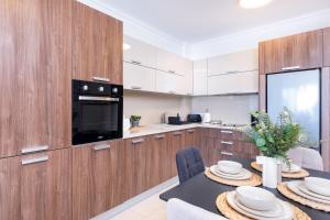 a kitchen with wooden cabinets and a table with chairs at Quattro Beachfront Sea View Ap 206 in Larnaka +12 photos