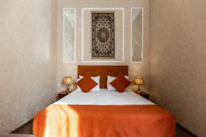 Nizami Boutique by La Casa في باكو: غرفة نوم بسرير وبطانية برتقالية ومصباحين
