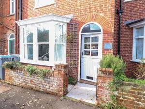 ein Backsteinhaus mit einer weißen Tür und einem weißen Fenster in der Unterkunft Fawcett Cottage in Aldeburgh