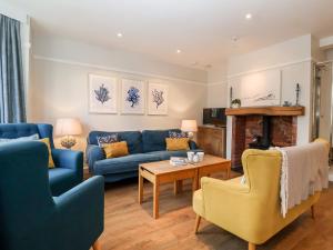 ein Wohnzimmer mit blauen Sofas und einem Tisch in der Unterkunft Fawcett Cottage in Aldeburgh