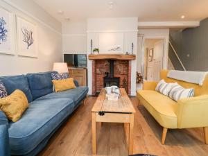 ein Wohnzimmer mit einem blauen Sofa und einem Tisch in der Unterkunft Fawcett Cottage in Aldeburgh