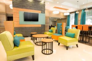 a waiting room with chairs and tables and a tv at Pear Tree Inn San Antonio Airport in San Antonio