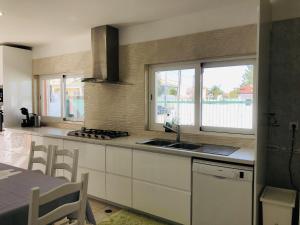 a kitchen with white cabinets and a sink and windows at AYAMI Villa in Setúbal