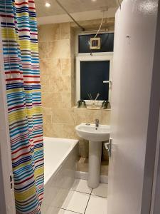 baño con lavabo y cortina de ducha en Huge and affordable 3 bedroom flat in Hammersmith for 6 people with breakfast en Londres