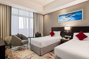 a hotel room with two beds and a chair at Ramada by Wyndham Dubai Barsha Heights in Dubai
