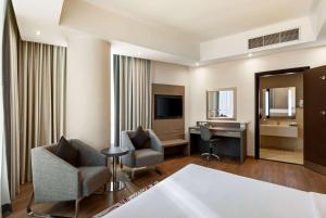 a hotel room with a desk and chairs and a television at Ramada by Wyndham Dubai Barsha Heights in Dubai