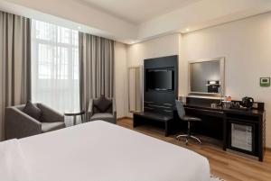 a hotel room with a bed and a desk and a television at Ramada by Wyndham Dubai Barsha Heights in Dubai