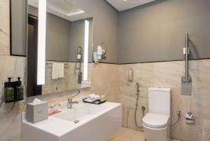 a bathroom with a sink and a toilet and a mirror at Ramada by Wyndham Dubai Barsha Heights in Dubai