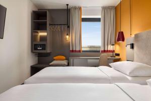 a hotel room with two beds and a window at Vienna House Easy by Wyndham Cracow in Krakow