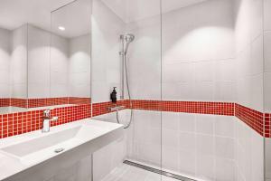 baño blanco con ducha y lavamanos en Vienna House Easy by Wyndham Cracow en Cracovia