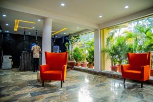 a lobby with two red chairs and a man standing in the background at Fritz Apartments & Suites in Abuja