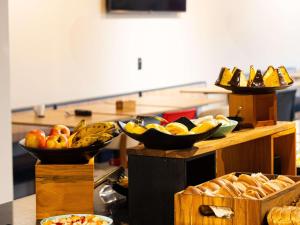a buffet with bowls of fruit and baskets of bread at ibis Barra do Garcas in Barra do Garças
