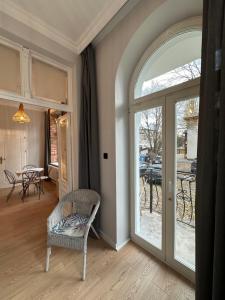 a living room with an arched glass door and a chair at Kamienica Ogrodowa Rooms in Sopot