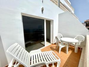 a balcony with white furniture and a table and chairs at Apartamento de 1 dormitorio frente al mar en Tamaduste in Tamaduste
