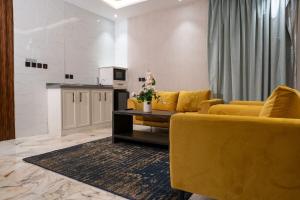 a living room with yellow furniture and a kitchen at لحظات الفندقية حراء in Jeddah