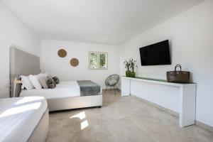 a white bedroom with a bed and a tv at Sopramare Resort in Piano di Sorrento