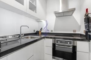 a white kitchen with a sink and a stove at Walaa Homes Elite Studio at Damac Esclusiva Tower Riyadh-401 in Riyadh