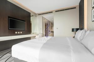 1 dormitorio con 1 cama blanca grande y TV de pantalla plana en Walaa Homes Elite Studio at Damac Esclusiva Tower Riyadh-401, en Riad