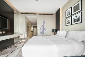 1 dormitorio con 1 cama blanca grande y TV en Walaa Homes Elite Studio at Damac Esclusiva Tower Riyadh-401, en Riad