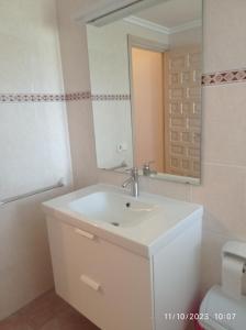 une salle de bains avec un lavabo blanc et un miroir dans l'établissement Apartamento Illa Blanca, à Es Pujols