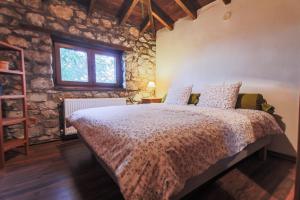 - une chambre avec un lit et un mur en pierre dans l'établissement Zeusplace Pierion Villa Elatochori, à Elatochori