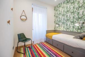 ein Schlafzimmer mit einem Bett und einem Stuhl auf einem bunten Teppich in der Unterkunft Lisbon Lapa Flat w/ Patio in Lissabon