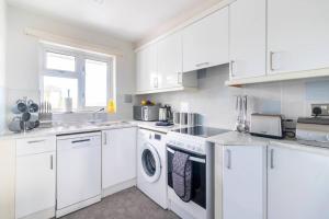 uma cozinha com armários brancos e uma máquina de lavar e secar roupa em WOW! SeaView Beach Apartment Sleeps 6-Free Parking em Bournemouth