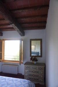 een slaapkamer met een bed, een spiegel en een dressoir bij Casa Tre Pini in Serravalle Pistoiese