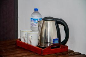 a tea kettle and two cups and a bottle of water at Sigiriya Free View Tree House & Villa in Sigiriya