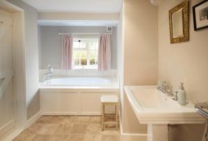 a bathroom with a tub and a sink and a window at Coral Cottage at Castle Howard in York