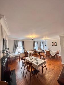 uma sala de jantar com mesas, cadeiras e janelas em Fiddlestone Bar and B&B em Belleek