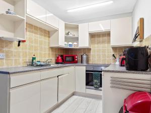 uma cozinha com armários brancos e um micro-ondas vermelho em 3 bed Cottage in the Heart of Ulverston em Ulverston