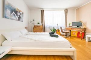 1 dormitorio con 1 cama blanca grande y escritorio en Willkommen in München nahe Zentrum und Oktoberfest en Múnich