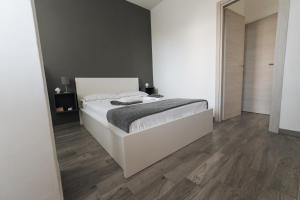 1 dormitorio con cama blanca y suelo de madera en Grey's Apartment, en Catania