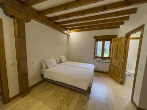 1 dormitorio con cama blanca y ventana en Posada Cabañes en Cabañes