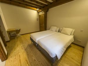 uma grande cama branca num quarto com uma secretária em Posada Cabañes em Cabañes