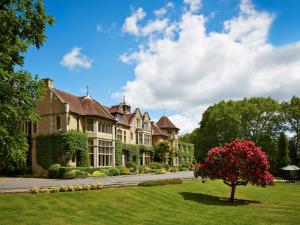 une grande maison avec un arbre dans l'herbe dans l'établissement Macdonald Frimley Hall Hotel & Spa, à Camberley