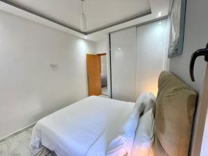 - une chambre avec un lit blanc et un miroir dans l'établissement A2 Appartement entièrement neuf au cœur de Témara, à Temara