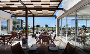 Un restaurante con mesas, sillas y ventanas. en Thalassa Beach Resort, en Trikomo