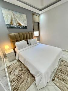 Un dormitorio con una gran cama blanca y una pintura en A2 Appartement entièrement neuf au cœur de Témara, en Temara