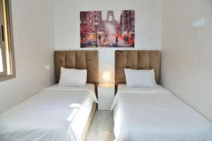 - 2 lits dans une chambre avec des draps blancs dans l'établissement Appartement entièrement neuf au cœur de Témara, à Temara