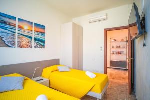 twee gele bedden in een kamer met een tv bij Alloggio Gallinara a due passi dal mare in Liguria in Albenga
