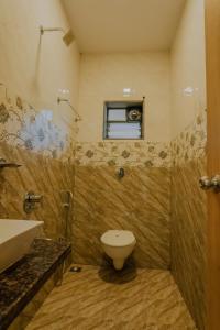 a bathroom with a toilet and a sink and a window at oakwood mahabaleshwar in Mahabaleshwar