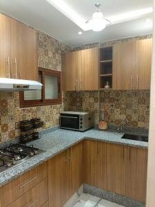 uma cozinha com armários de madeira e um micro-ondas em Aourir's new appartement em Agadir