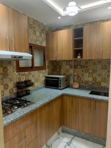 uma cozinha com armários de madeira e um micro-ondas em Aourir's new appartement em Agadir