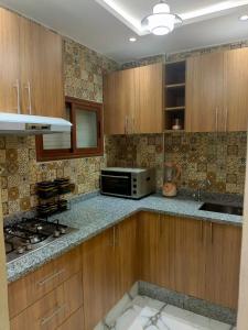 a kitchen with wooden cabinets and a microwave at Aourir's new appartement in Agadir