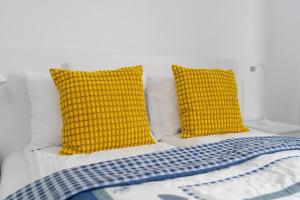 Una cama con dos almohadas amarillas. en Traditionally Furnished Apartment with Balcony in Poznan by Renters en Poznan