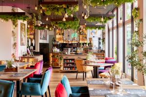 a restaurant with tables and chairs and plants at Trihotel Rostock - Wellnesshotel Adults Only in Rostock