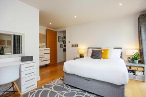 a bedroom with a white bed and a desk at Veeve - Here Comes the Sun in London