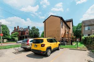 a yellow suv parked in a parking lot in front of a house at Comfortable and Walkable - Off-Street Parking in Pittsburgh